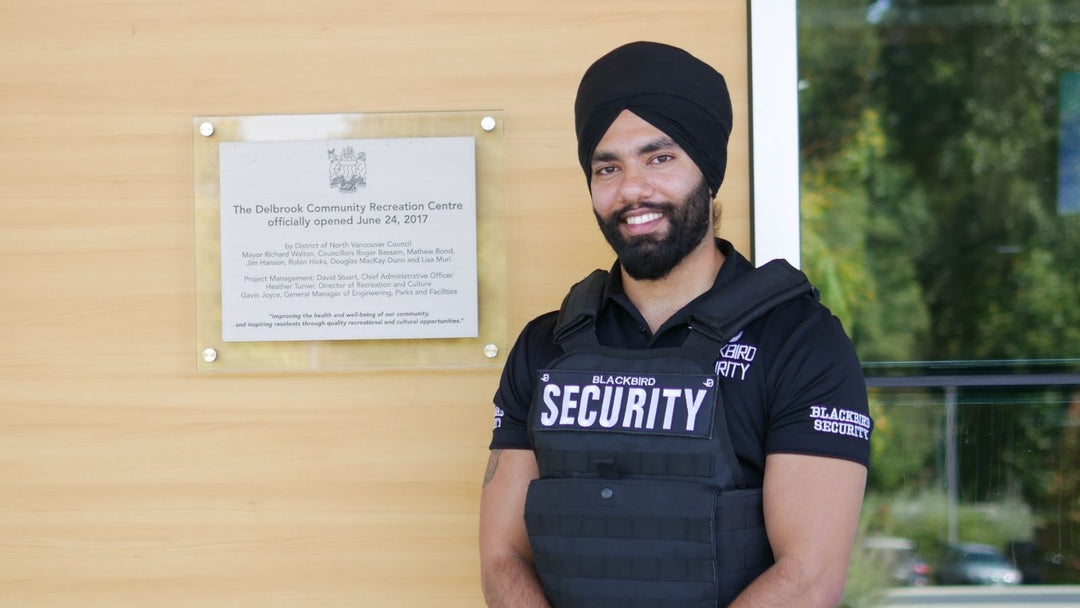 Uniformed Blackbird security guard standing in front of sign on wall