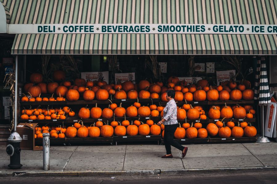 person walking in front of store with pumpkins