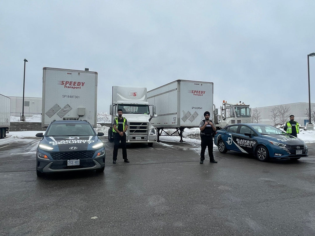 Three Uniformed Blackbird security guards in front of Mobile patrol car and transport trucks