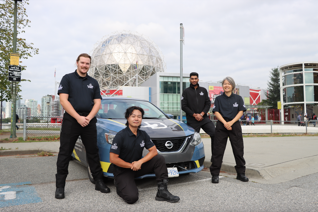 Four security guards pose in front of a mobile patrol security vehicle in Vancouver