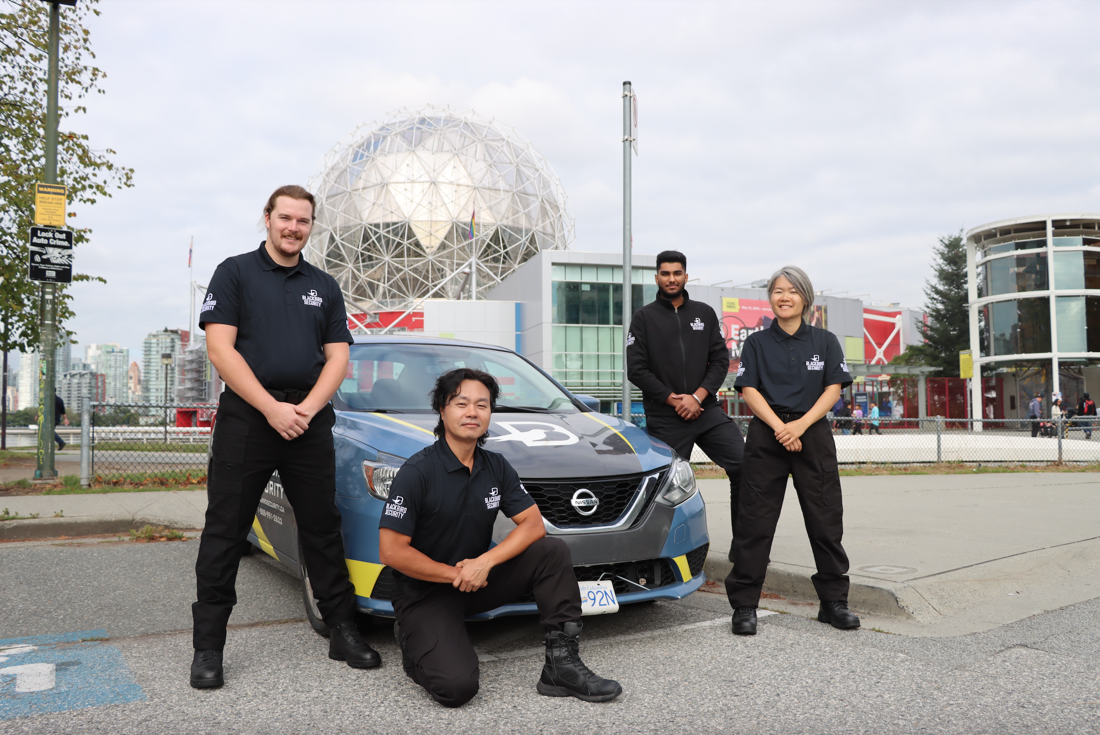 Four security guards pose in front of a mobile patrol security vehicle in Vancouver