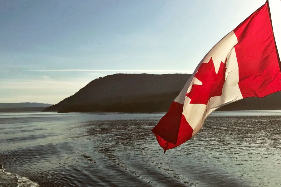 Canadian flag flying off boat crossing water