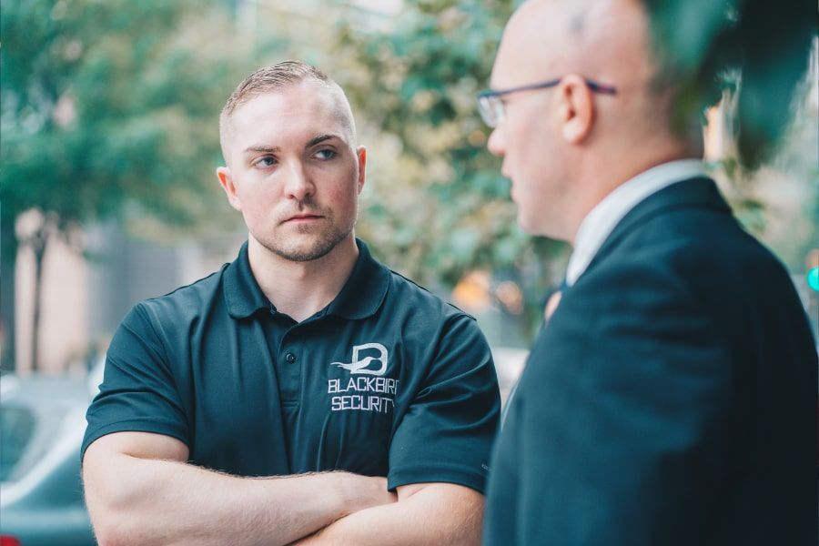 Uniformed Blackbird security guard listening to man in suit talk