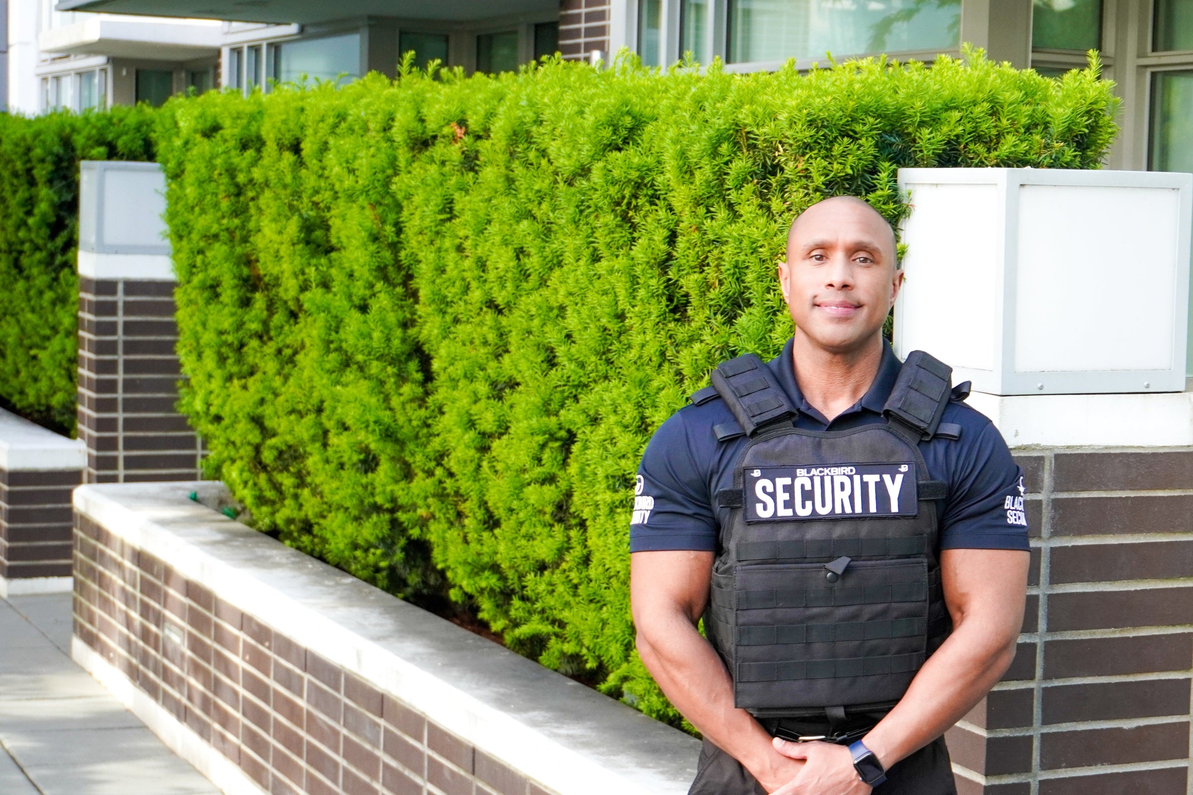 Uniformed Blackbird security guard standing in front of building