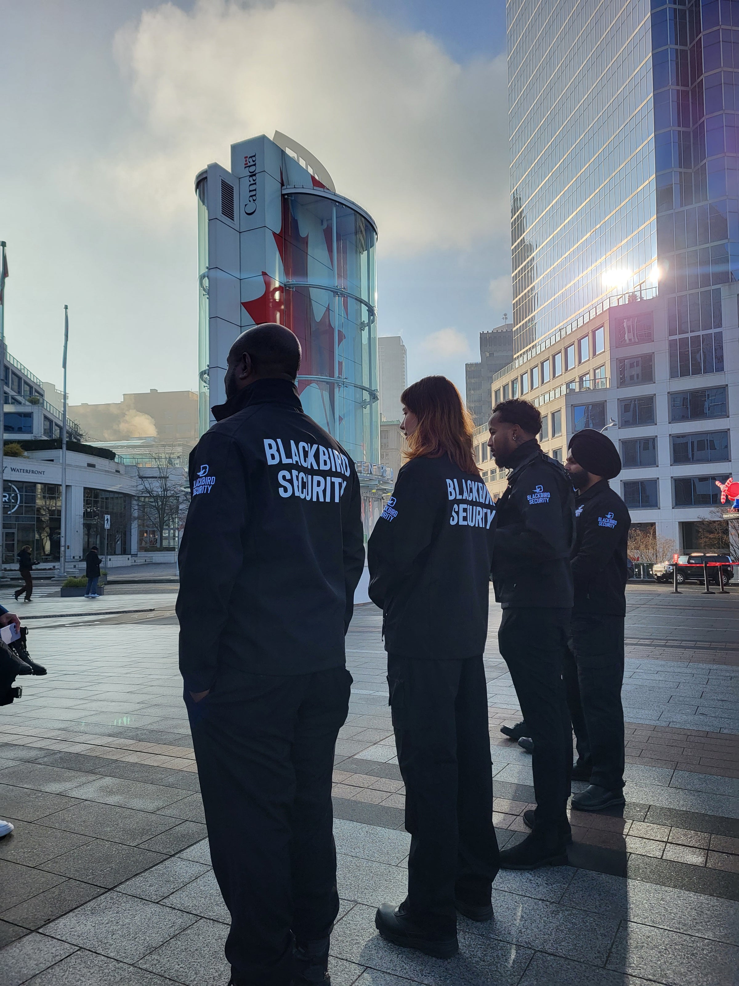 Four uniformed Blackbird security guards standing in front of building