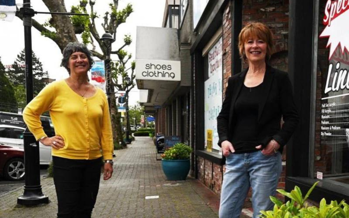 two women standing on street in front of stores
