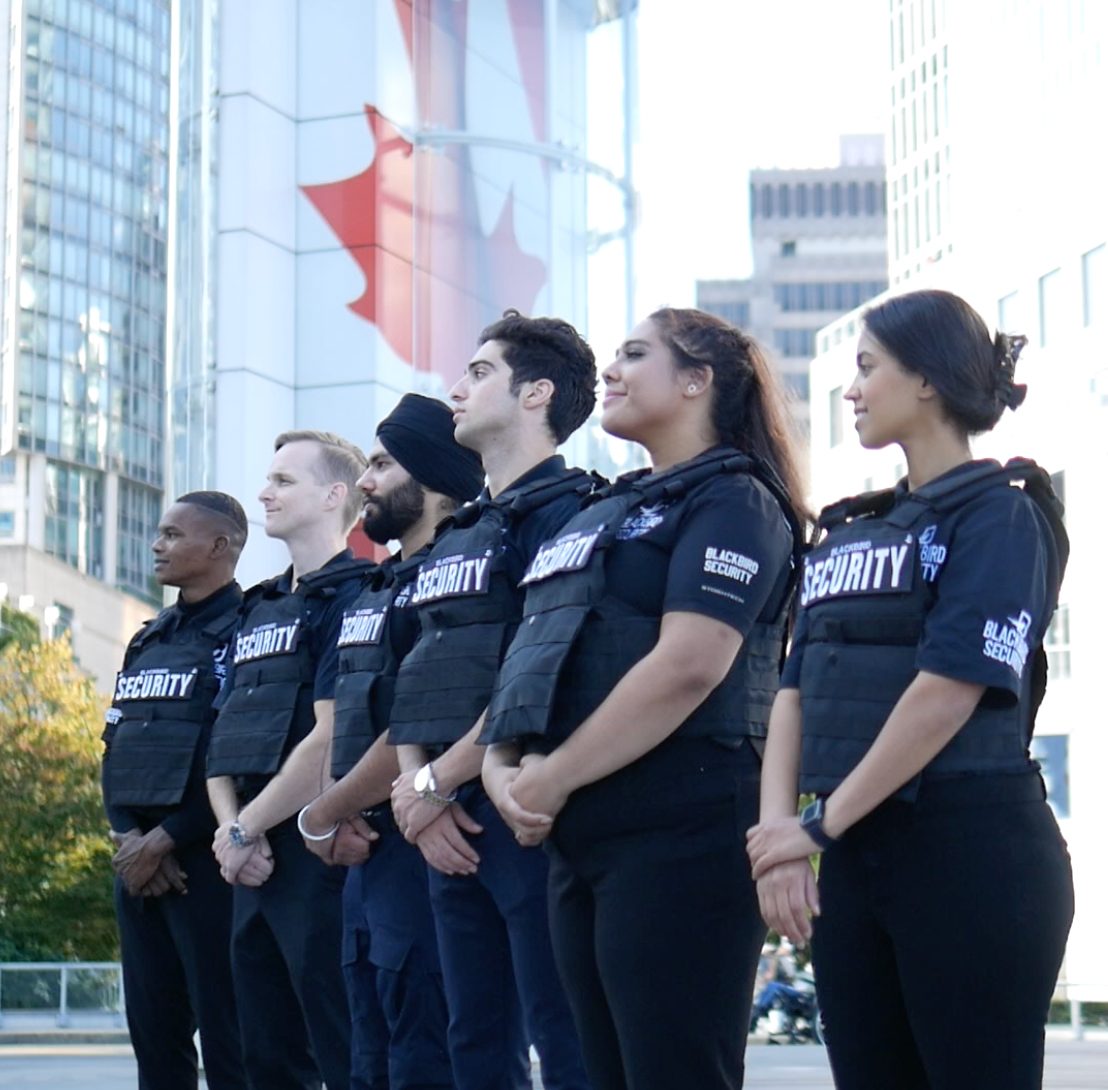 Six Uniformed Blackbird security guards standing in front of building