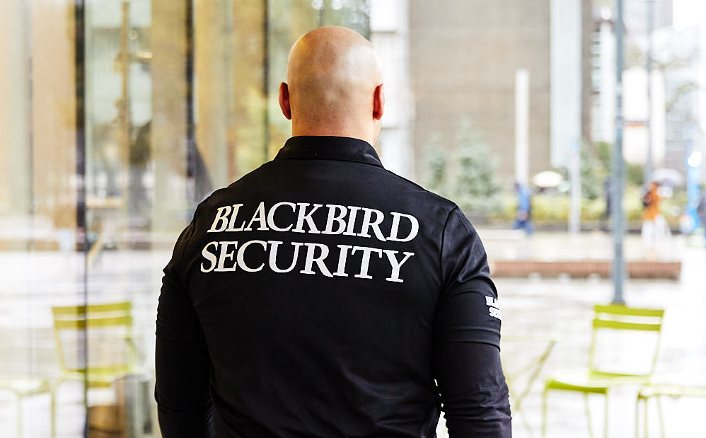 Uniformed Blackbird security guard walking down street on patrol
