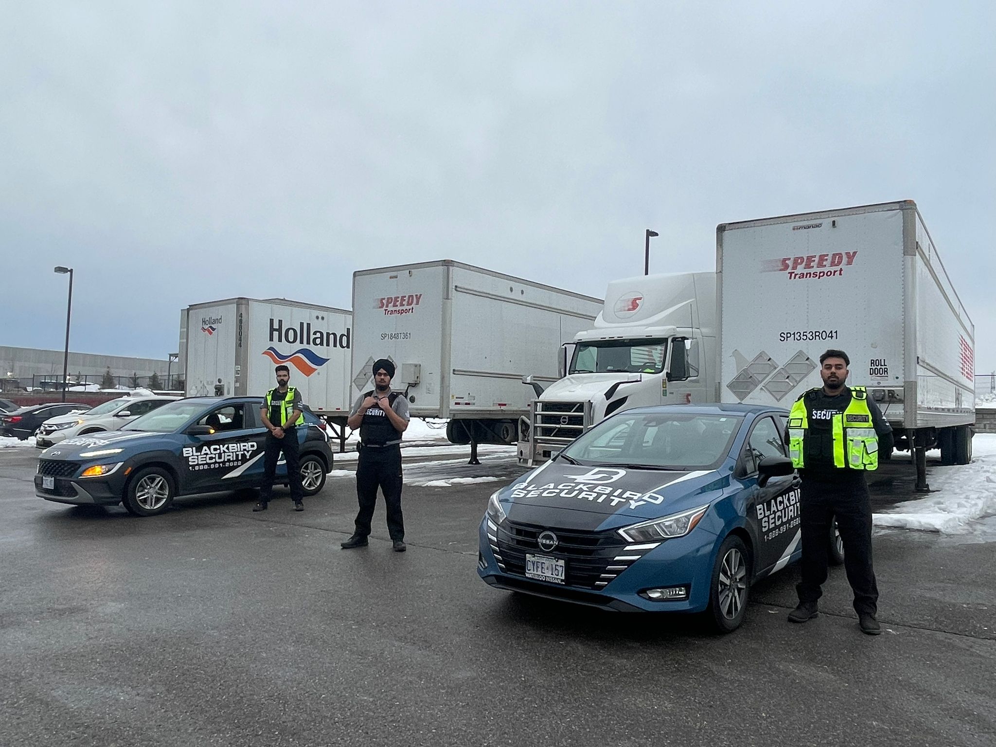Three Uniformed Blackbird security guards in front of two Mobile patrol cars in truck parking lot