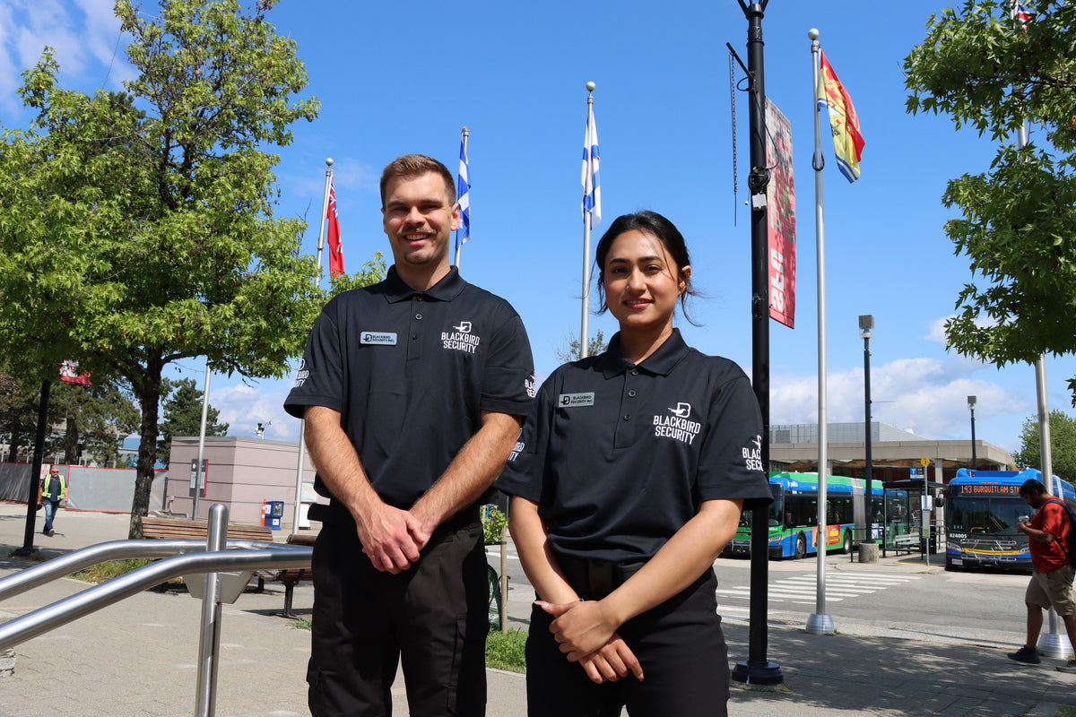Two Uniformed Blackbird security guards standing in front of flagpoles