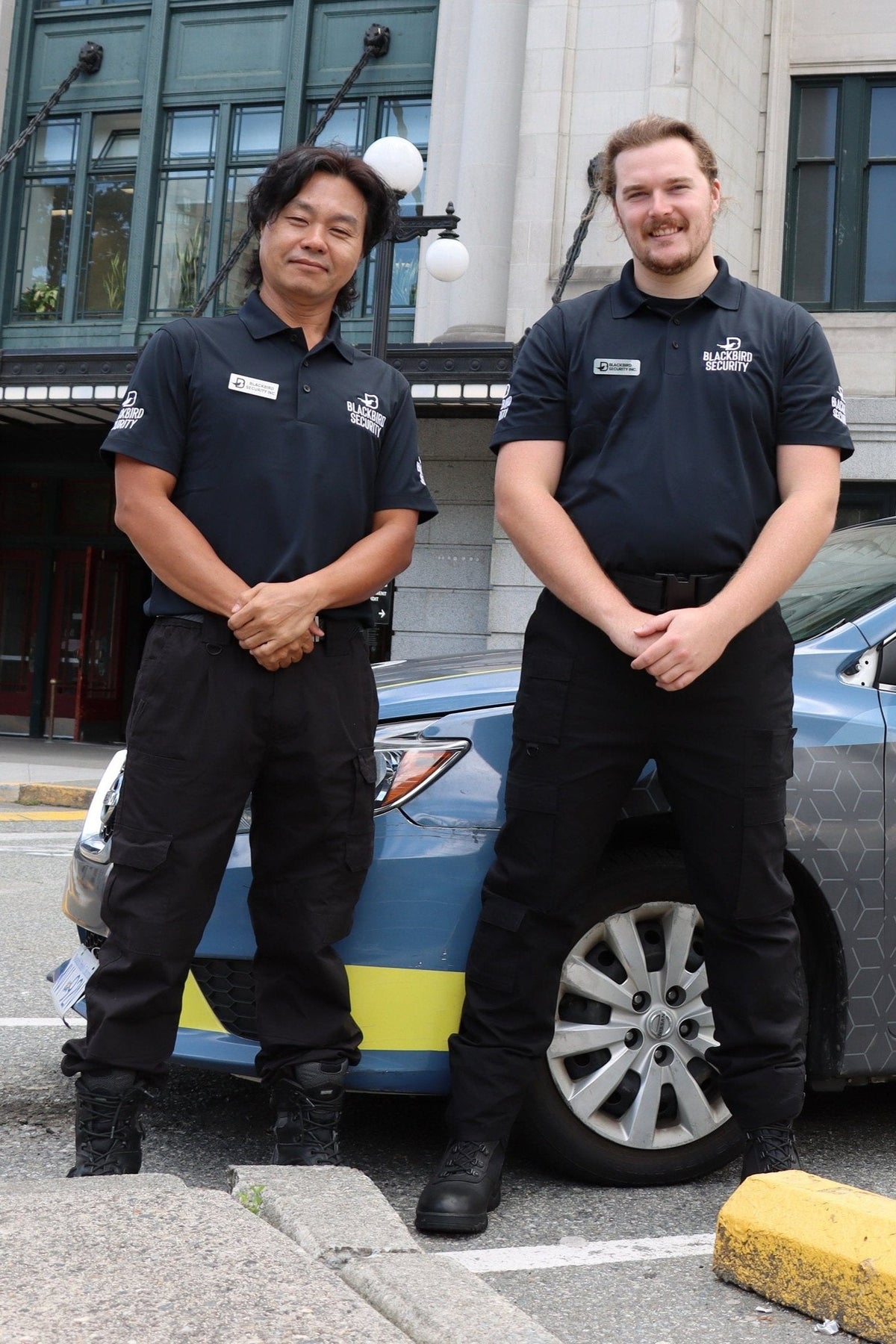 Two Uniformed Blackbird security guards in front of Mobile patrol car