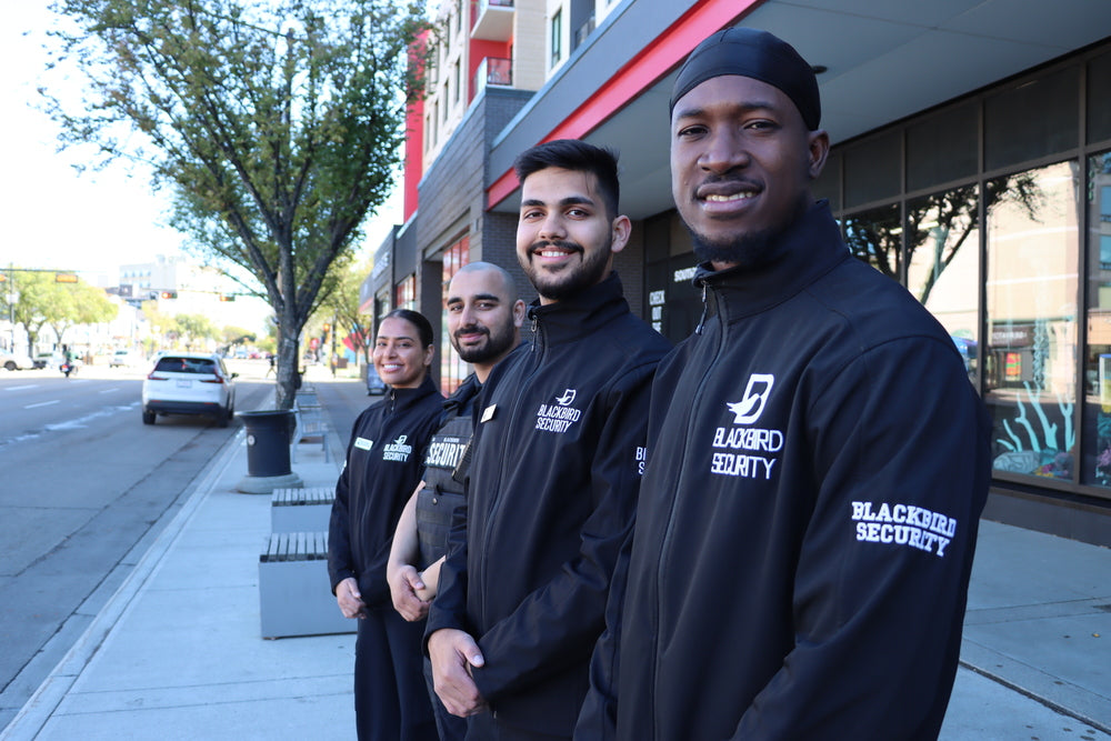 Four security personnel in Blackbird Security uniforms standing on a city street.