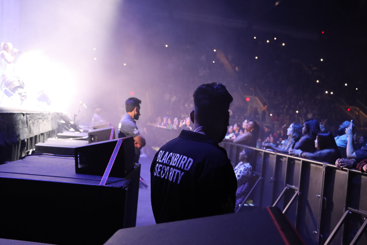 Uniformed Blackbird security guards in front stage at concert doing crowd control