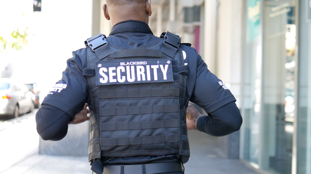 Uniformed Blackbird security guard walking down street