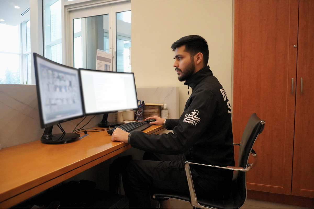 Blackbird Security guard monitoring security feeds on dual screens