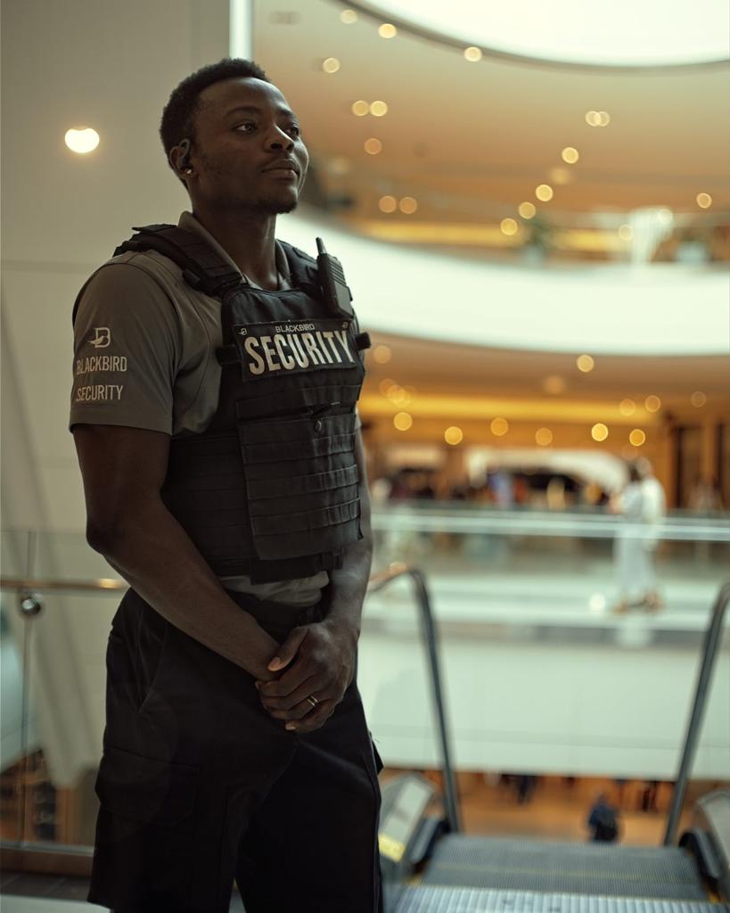 Blackbird security guard standing at top of escalator in shopping mall