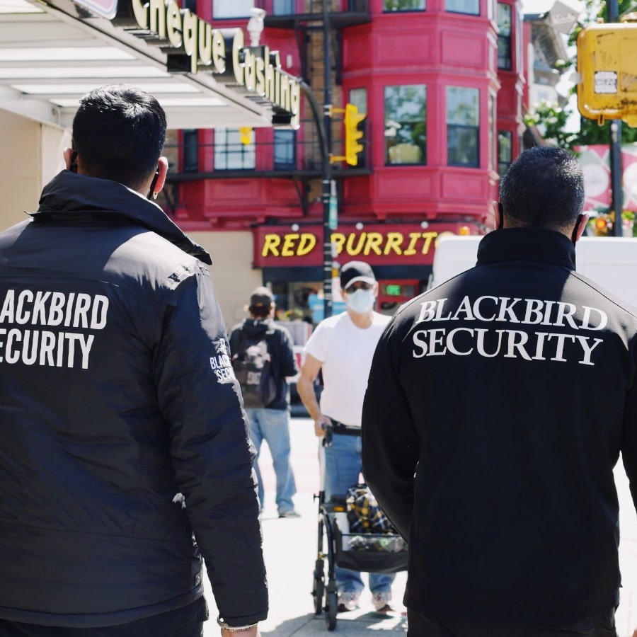Two Uniformed Blackbird security guards on walking down urban street