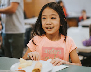 young girl eating at table