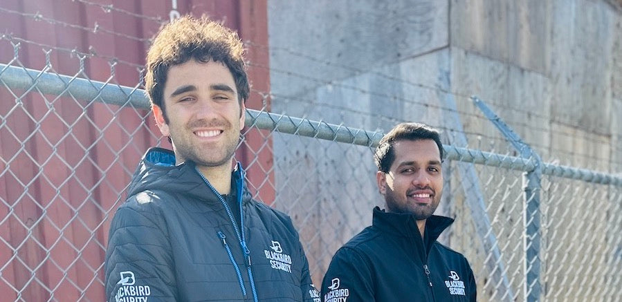 Two Blackbird Security guards standing by fence