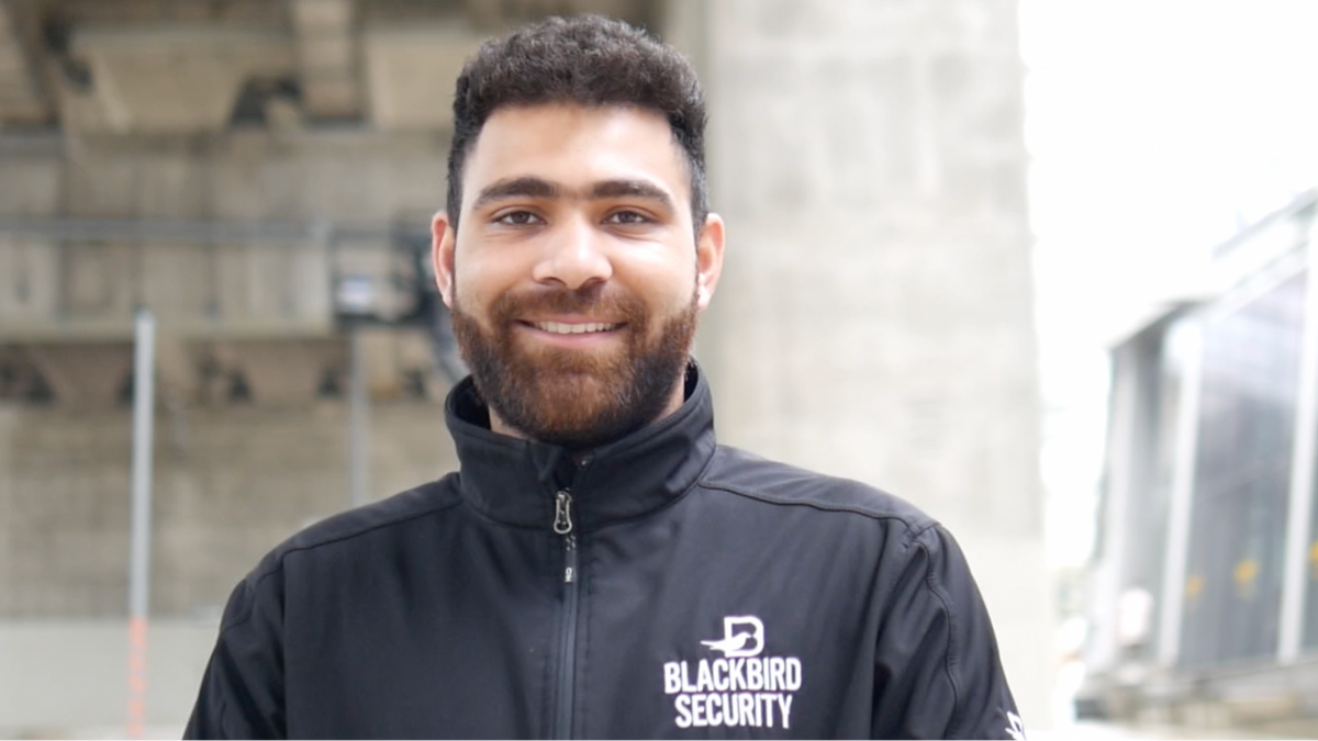 Man wearing a Blackbird Security jacket standing outdoors.