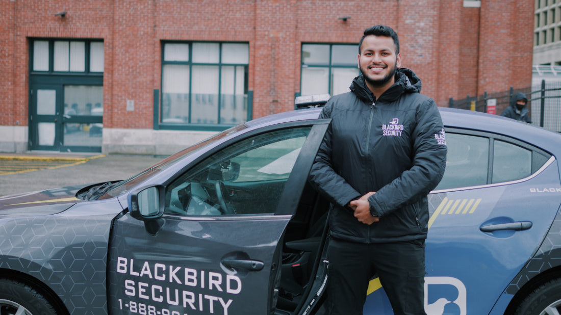 Uniformed Blackbird security guard in front of Mobile patrol car