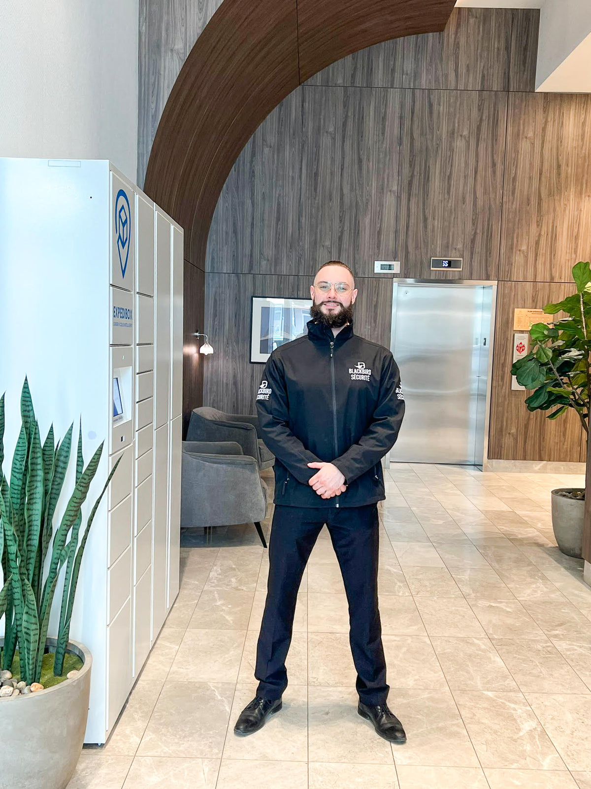 Bearded blackbird security guard standing in apartment building lobby